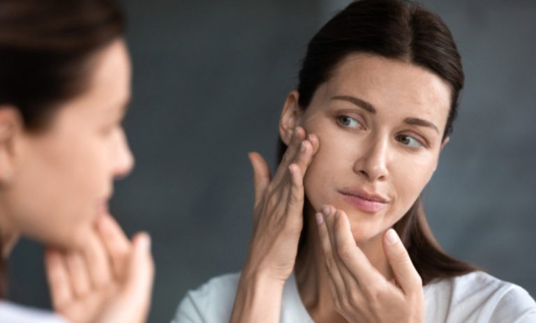 Woman looking in mirror considering treatments for Dry Skin Condition