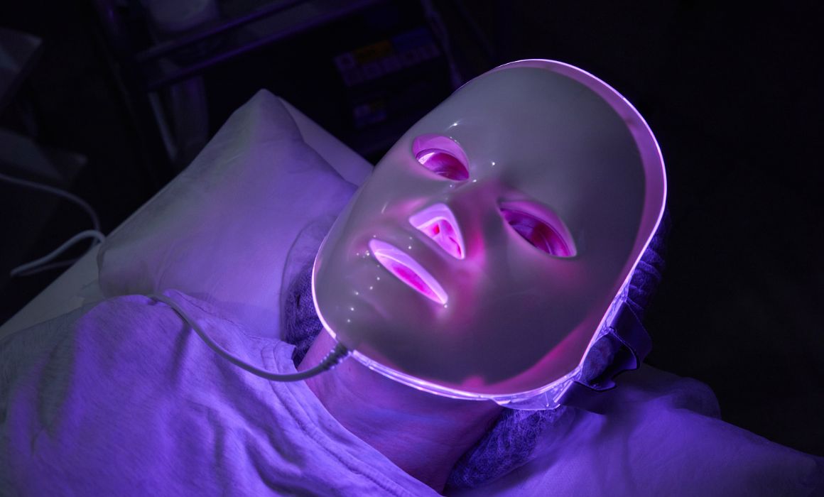 woman laying on bed with blue light LED mask