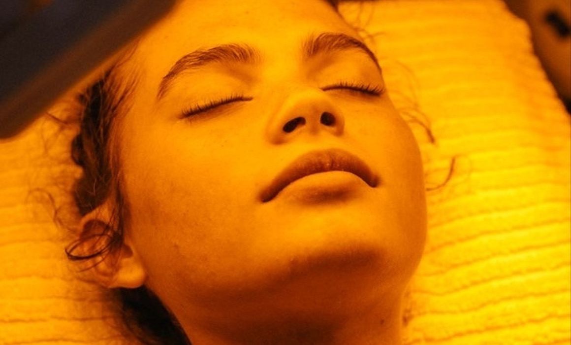 close up of a woman laying in bed receiving LED treatment