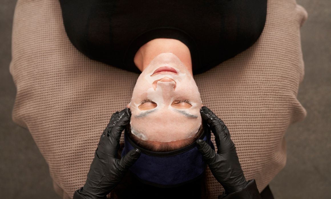 Female client on massage table receiving facial by dermal clinician